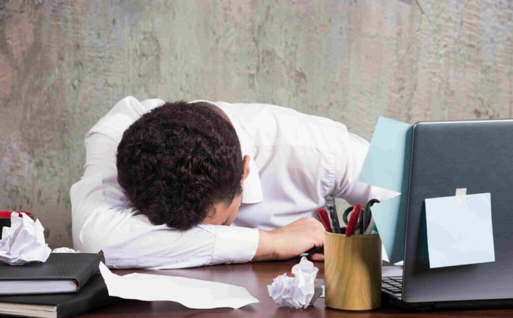 An office worker falls asleep at their desk due to exhaustion after a long and busy day. This condition highlights the importance of body recovery for office workers to help the body relax again and maintain productivity.